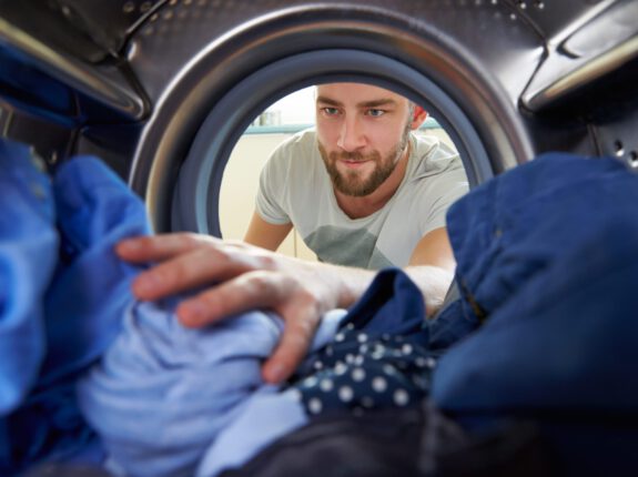 Man vult wasmachine met kleding