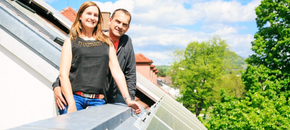 Man en vrouw poseren op balkon, omringd door dak met zonnepanelen