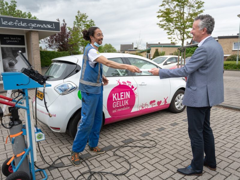 De medewerker van BandenOpSpanning geeft papieren aan wethouder Jan Smits