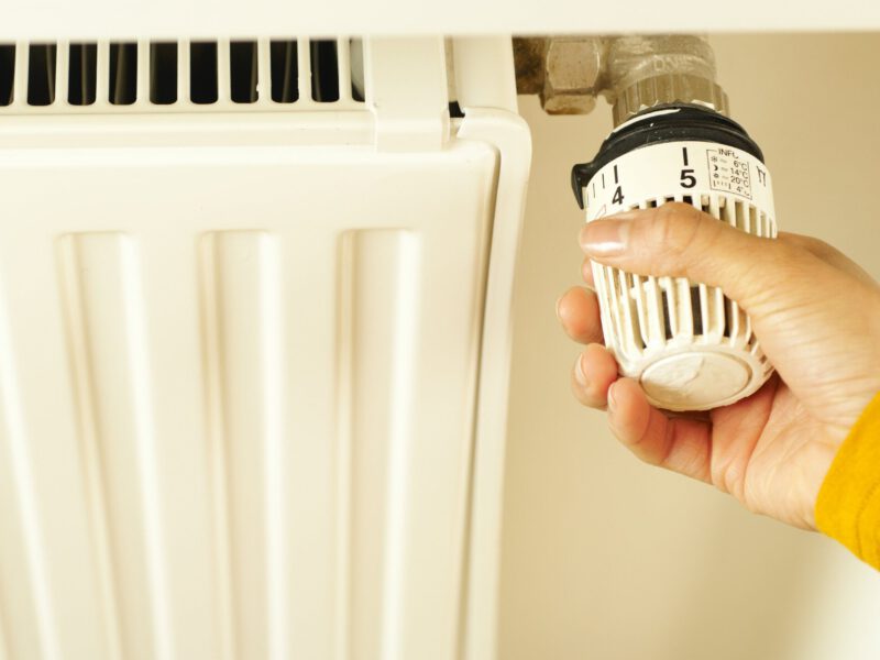 Hand draait aan temperatuurknop radiator