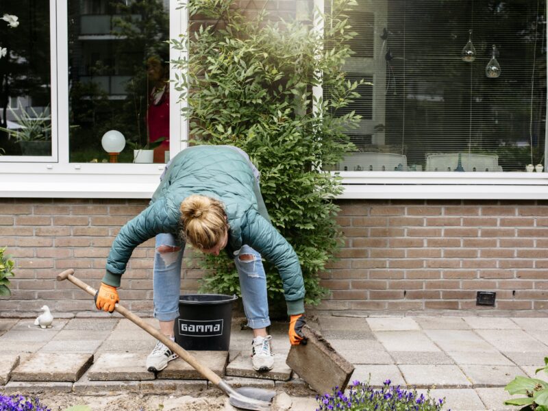 Vrouw verwijdert tegels uit de voortuin